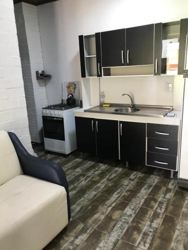 a kitchen with black cabinets and a sink and a couch at Sitio dos Rochedos in Ivoti