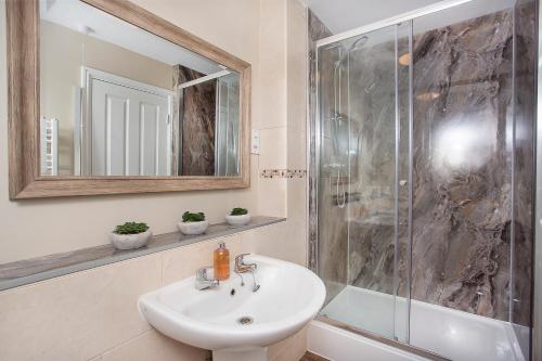 a bathroom with a sink and a shower with a mirror at Knavesmire Mews 3 bedrooms-Free parking in York