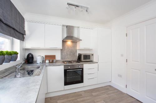 a kitchen with white cabinets and a stove top oven at Knavesmire Mews 3 bedrooms-Free parking in York