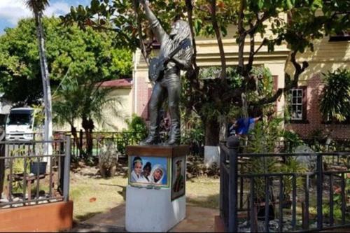 a statue of a man reaching up into a tree at The Mango Lodge in Kingston
