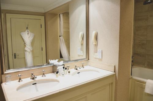 un bagno con due lavandini e un grande specchio di Melbourne Lodge a Welwyn