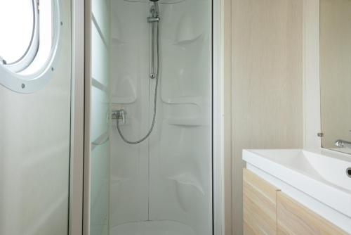 une salle de bain blanche avec une douche et un lavabo dans l'établissement Camping Le Moténo - Maeva, à Plouhinec