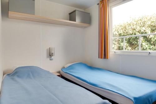 un lit dans une chambre avec une fenêtre dans l'établissement Camping Le Moténo - Maeva, à Plouhinec