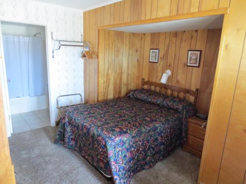 a bedroom with a bed and a wooden wall at Lake 'N Pines Motel in Cooperstown