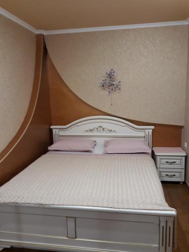 a bedroom with a white bed with pink pillows at Comfortable Apartment in Kremenchuk