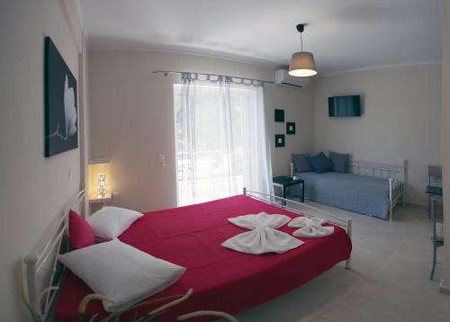 duże czerwone łóżko w pokoju z kanapą w obiekcie Lalezas Studios w mieście Tolo