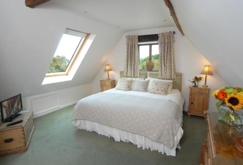 a bedroom with a white bed and two windows at Sheepscombe Byre in Snowshill