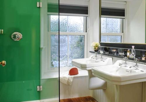 un baño verde y blanco con 2 lavabos y una ventana en The Dunraven, Adare, en Adare