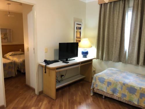 a hotel room with a desk with a television on it at Residencial Bella Vista Suites in Sao Paulo