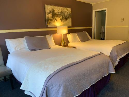 two beds in a hotel room next to a lamp at Starlite Motel & Suites in Big Indian
