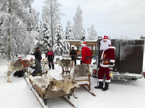 a man dressed as santa claus standing next to a herd of deer at Svanstein Lodge in Svanstein