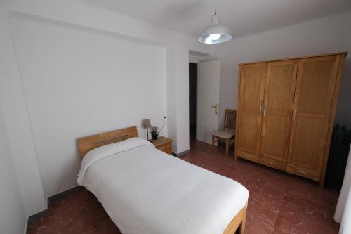 een slaapkamer met een wit bed en een houten kast bij Apartament Tarracoliva in Tarragona