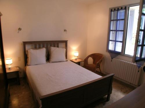 アヴィニョンにあるAu charme et à la campagneのベッドルーム1室(ベッド1台、テーブル2台、窓2つ付)