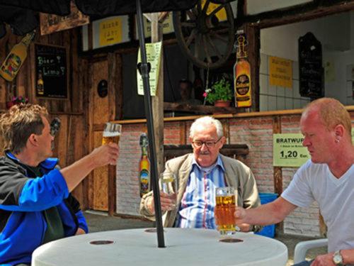 three men sitting at a table with glasses of beer at Fränkischer Hof in Mainleus