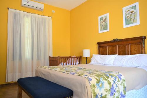 a bedroom with a bed and a yellow wall at Posada del Olivo in Nonogasta