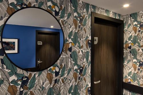 a mirror on a wall next to a bathroom door at Les Nomades Beaune in Beaune