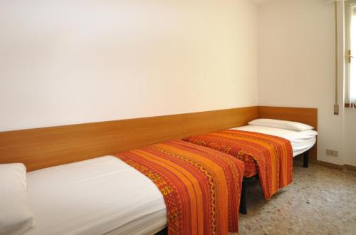2 letti in una camera con coperte arancioni di Condominio Aurora a Bibione