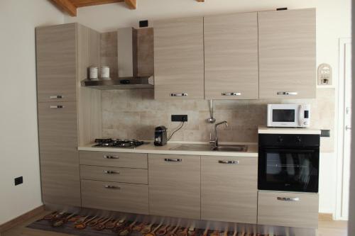 a kitchen with wooden cabinets and a sink and a microwave at "Sutt'e su sole" - Vacanza nel cuore della Sardegna in Siamanna