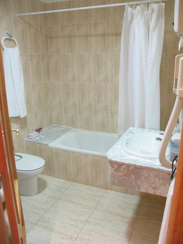 a bathroom with a tub and a toilet and a sink at Hostal Imperial in Crevillente