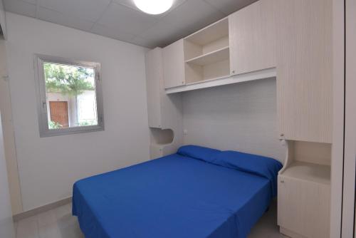 a bedroom with a blue bed and white walls at Camping Johnny in Marina Palmense