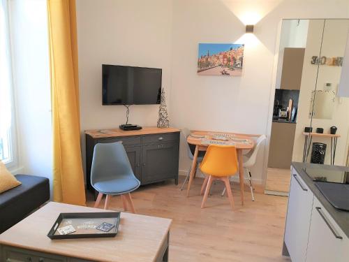 ein Wohnzimmer mit einem TV, einem Tisch und Stühlen in der Unterkunft HYPERCENTRE/LAMARTINE APPART 211 in Nizza