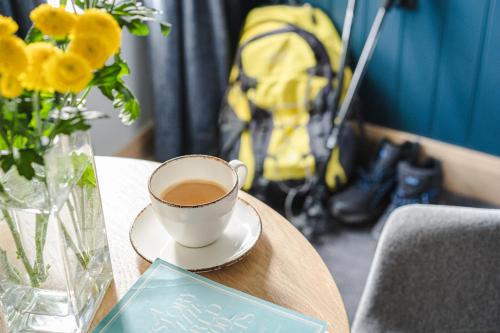 a cup of coffee on a table with a vase of flowers at Hillyard House Hotel in Castlewellan