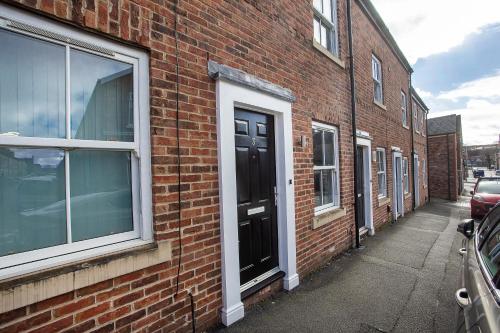 a brick building with a black door on a street at Knavesmire Mews 3 bedrooms-Free parking in York