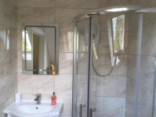a bathroom with a shower and a sink and a mirror at Moorclose Bed and Breakfast in St Bees