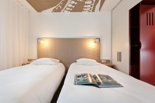 two beds in a room with a book on them at ibis Styles Lille Aéroport in Lesquin
