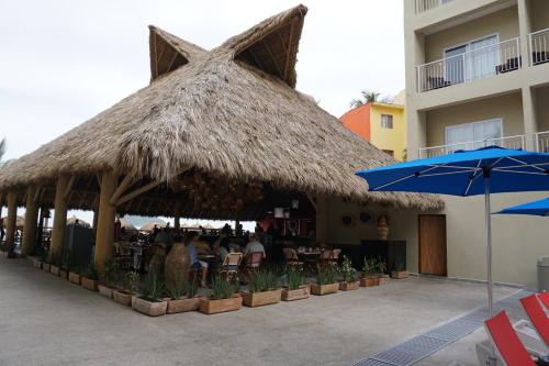 a restaurant with a straw umbrella and tables and chairs at Decameron Isla Coral Guayabitos, Ramada All-Inclusive Resort in Rincon de Guayabitos
