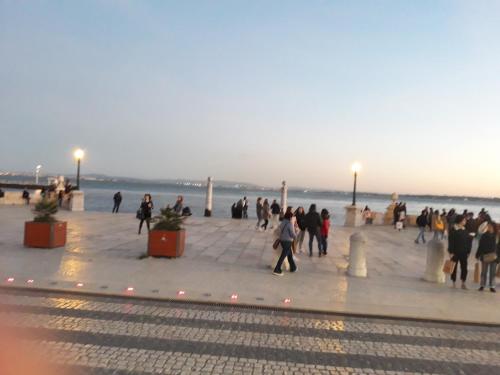 a group of people walking on a sidewalk near the beach at Ameli Rooms in Lisbon