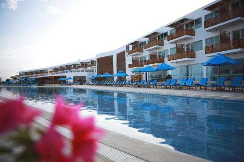 a swimming pool with blue umbrellas and chairs and a hotel at San Agustin Paracas in Paracas