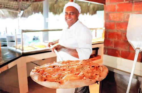 a man standing in front of a large pizza at Catalonia Bayahibe - All Inclusive in Bayahibe