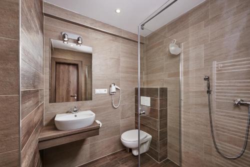 a bathroom with a toilet and a sink and a shower at Hotel Studničky in Vernár