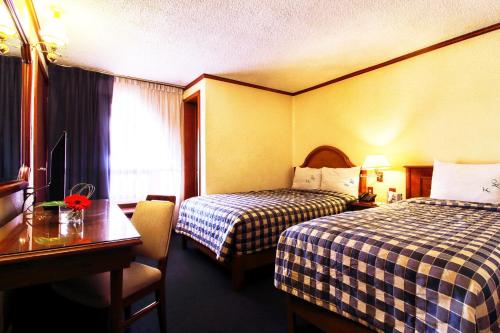 a hotel room with two beds and a table at Hotel Lastra in Puebla
