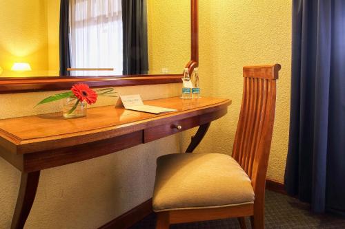 a desk with a red flower on it in a room at Hotel Lastra in Puebla