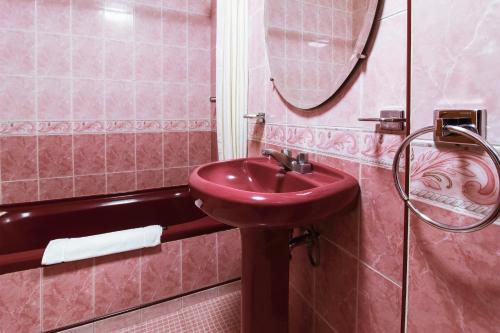 a pink bathroom with a sink and a shower at Hotel Lastra in Puebla