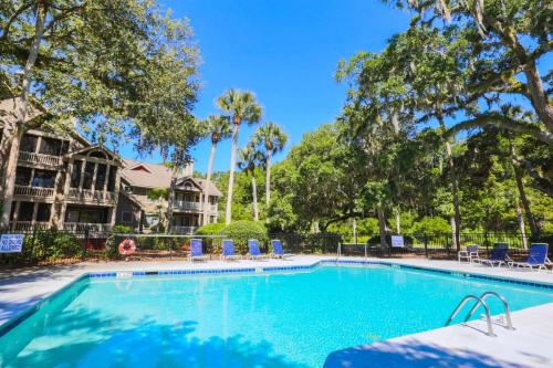 a large swimming pool with chairs and trees at Rue De Buci in Johns Island