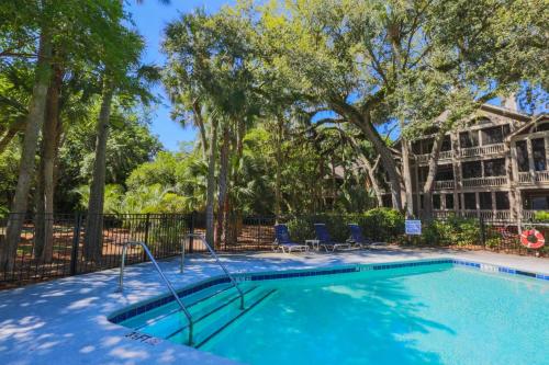 a swimming pool with two chairs and trees at Rue De Buci in Johns Island