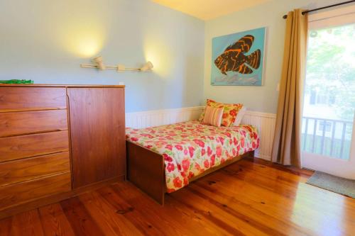 a bedroom with a bed and a dresser and a window at Decked Out in Sullivans Island