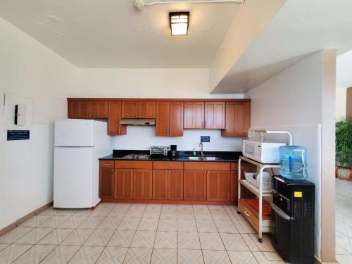 a kitchen with wooden cabinets and a white refrigerator at Borinquen Beach Inn in San Juan