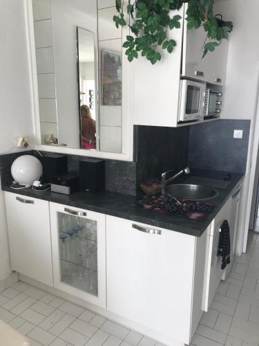 La cuisine est équipée de placards blancs, d'un lavabo et d'un miroir. dans l'établissement PORT NATURE 2 Village Naturiste, au Cap d'Agde