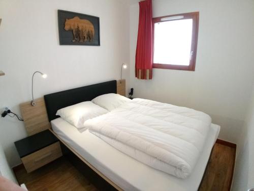 ein weißes Bett in einem Zimmer mit Fenster in der Unterkunft Au bon endroit N1 - Appartement 2 pièces 7 personnes - proche pistes - coeur station - balcon in Orcières