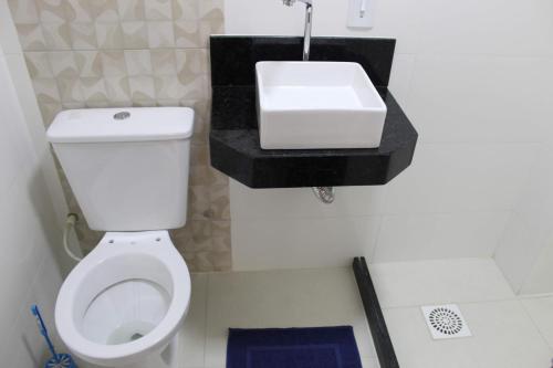 La salle de bains est pourvue de toilettes blanches et d'un lavabo. dans l'établissement Ap novo a 90m da praia, à Guarapari