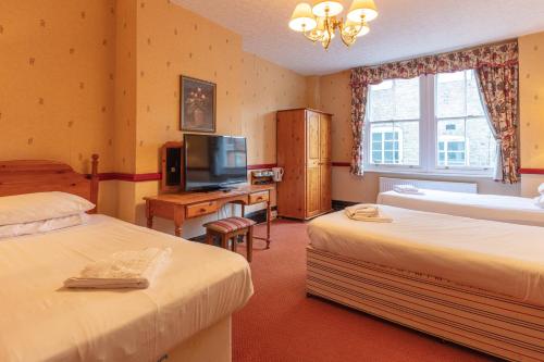 a hotel room with two beds and a television at The New Inn by Roomsbooked in Gloucester