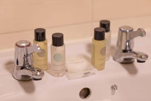 a bathroom sink with three bottles of soap and two faucets at The New Inn in Gloucester