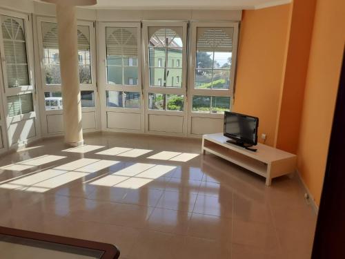 sala de estar con TV y algunas ventanas en Apartamento Playa da Langosteira, en Finisterre