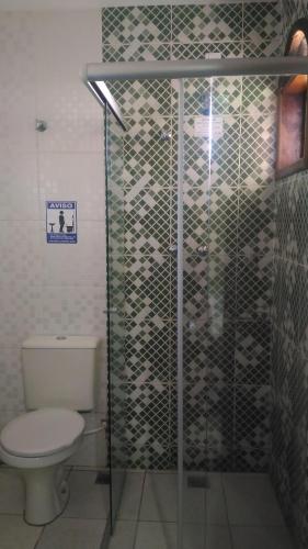 a bathroom with a toilet and a glass shower at Hotel Porto Real in Pôrto Real