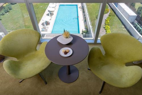two chairs and a table in a room with a pool at The Grand Hotel in Punta del Este