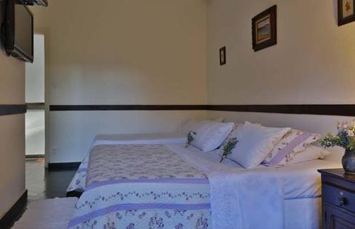 a bedroom with a bed with white sheets and pillows at Solar dos Ipês in Serra do Cipo